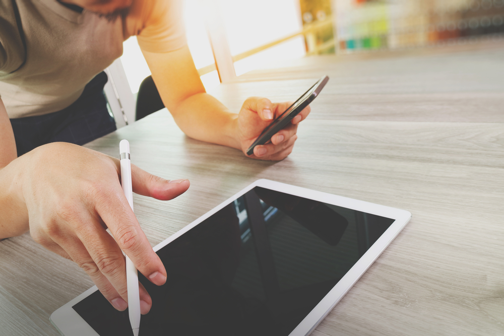 top view of Designer hand working with digital tablet computer and smart phone on wooden desk as responsive web design concept