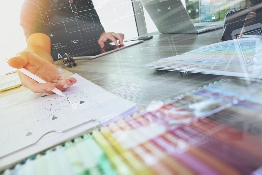 two colleagues interior designer discussing data and digital tablet and computer laptop with sample material and digital design diagram on wooden desk as concept